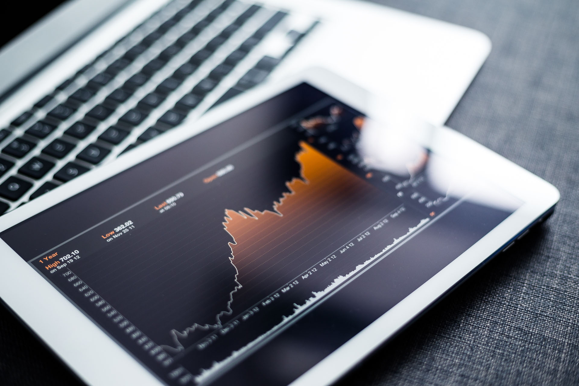 Tablet displaying a chart of stock movement, resting on a laptop.